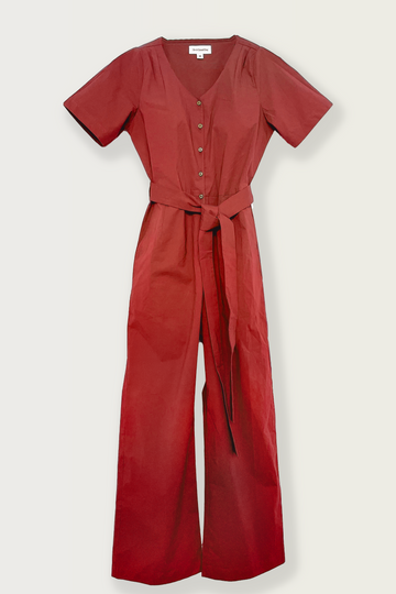 A front view product photo of the On A Good Day Revel Jumpsuit, made for petite women, in the shade Paprika. The jumpsuit features a V-neck opening, pleat details on the shoulders, coconut shell buttons, a tie belt, seam pockets, and is ankle length. The Revel Jumpsuit is designed for short women, up to 160cm in height.